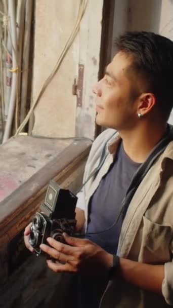 Asyalı Erkek Fotoğrafçının Terk Edilmiş Binanın Penceresinden Retro Kamerayla Fotoğraf — Stok video