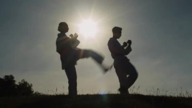 Gün batımında dövüş sanatları dövüşçülerinin siluetlerini denemek zor iş.