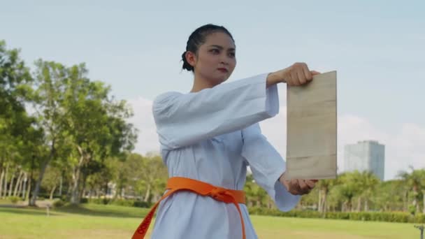 公園でテコンドー相手と仕事をしている間 白い制服を着た若いアジアの少女の中型ショット — ストック動画