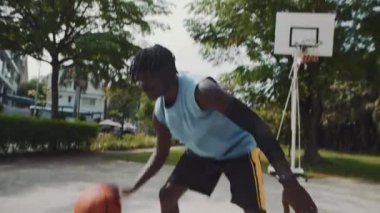 İki erkek Afrika kökenli Amerikalı sporcunun dışarıda sokak basketbolu oynamalarının el kamerası görüntüsü.