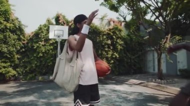 Dışarıda sokak basketbolu oynamak için buluşan iki erkek arkadaşın orta uzunlukta el sıkışması.
