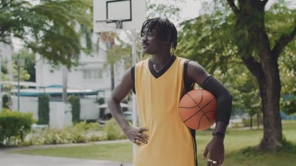 在室外操场上摆姿势拍照时拿着球的快乐黑人街头球运动员的画像 — 图库视频影像