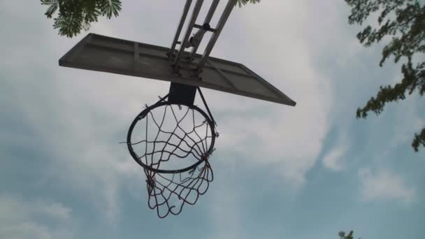 誰もいない空の背景にネットとバスケットボールのボールが付いているストリートボールのリングの直下の眺め 動画クリップ
