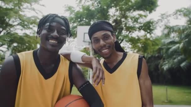 バスケットボールのトレーニング中にカメラのためにポーズする2人のアフリカ系アメリカ人の友人の中型の肖像画 ロイヤリティフリーのストック動画