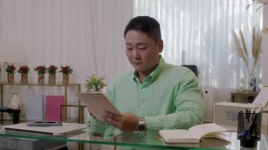 İş yerinde dijital tablet kullanan Asyalı erkek güzellik salonu müdürünün orta boy portresi.