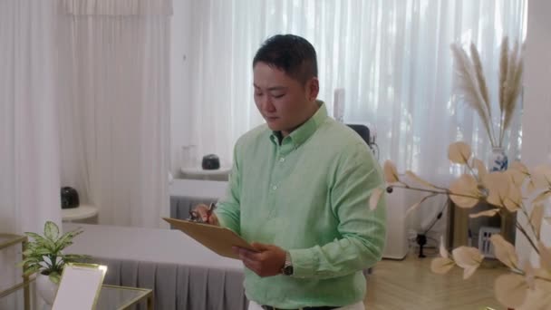 Середній Знімок Серйозного Чоловіка Азіатського Працівника Салону Краси Заповнює Документ Ліцензійні Стокові Відео