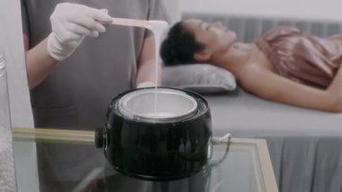 Spa salonundaki saç temizleme prosedürü için spatulayla karıştırılmış, tanınmayan bir uzman eritme ve balmumu.