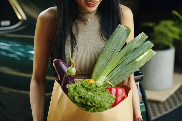 新鮮な食料品の袋を持っている笑顔の女性のクロップされたイメージ ストック写真