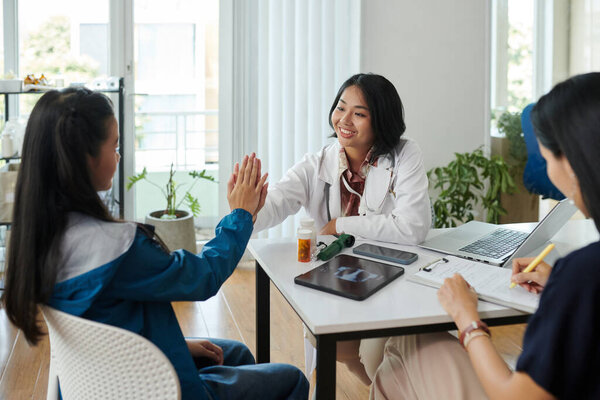 Pediatrician giving teenage patient high five to reassure her