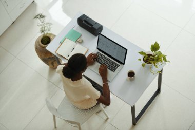 Genç bir kadın evdeki masada oturuyor ve dizüstü bilgisayardaki takvime bakıyor.