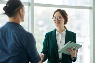 Neşeli iş kadını ofiste yeni meslektaşını selamlıyor.