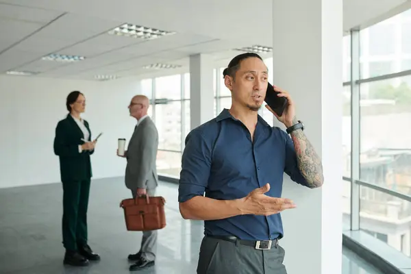 Empresario Tomando Teléfono Cuando Los Compañeros Trabajo Tienen Una Pequeña Imagen de stock