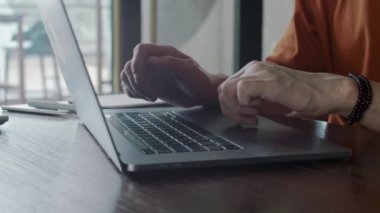 Kapalı alanda çalışan ve dizüstü bilgisayarda yazan tanınmayan girişimcilerin ellerini kapatın.