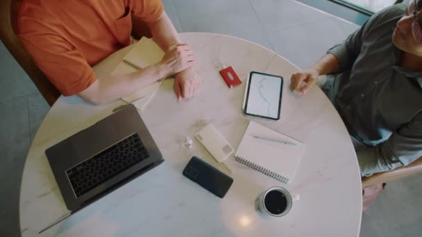 オフィスの円卓に座っているプロジェクトの詳細を議論しながら 2人の財務アナリストのトップビュー — ストック動画