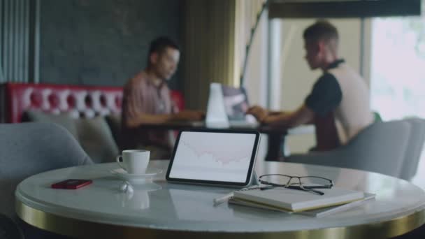 与两位在咖啡店讨论背景业务的创业者合作 专注于数字平板电脑桌面上的交易屏幕 — 图库视频影像