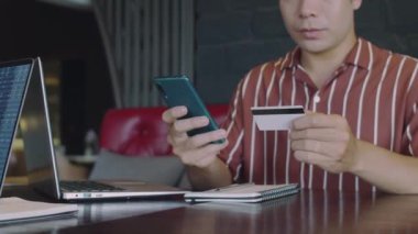 Erkek yatırımcının kapalı alanda ticaret yaparken kredi kartıyla online cüzdanından banka hesabına para transferi yaparken görüntüsü kesilmiş.