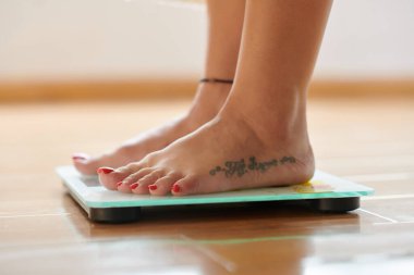 Cropped image of woman standing on scales, checking her weight clipart