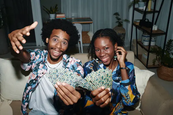 快乐的年轻黑人夫妇在家里摆姿势玩牌 免版税图库图片
