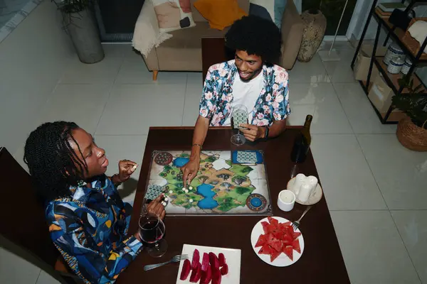 玩棋盘游戏时喝新鲜水果的黑人夫妇 图库照片