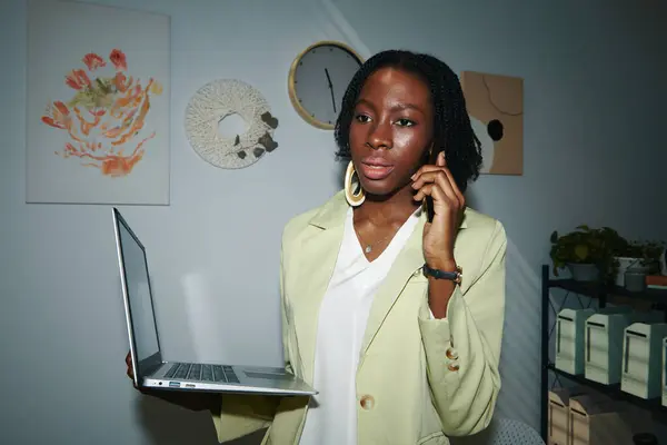 Retrato Empreendedor Preto Sério Com Laptop Falando Por Telefone Com Fotografias De Stock Royalty-Free