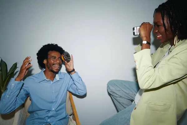 Gülümseyen Yaratıcı Siyahi Kadın Ofiste Arkadaşının Fotoğrafını Çekiyor Stok Resim