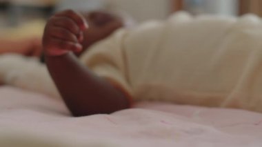 Bej elbiseli küçük bir kızın yatak örtüsünde dinlenirken etrafına bakınması.