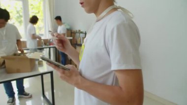 Bağış merkezinde ekip halinde çalışırken, dijital tablet üzerinde gönüllü erkek formunun kırpılmış görüntüsü.
