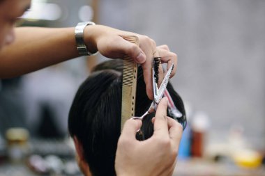 Berberin, müşterilerin saçlarını kestiği yakın plan görüntüsü.