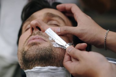 Bıyık bölgesini temizlemek için bıçak kullanan berberin görüntüsü kapanıyor