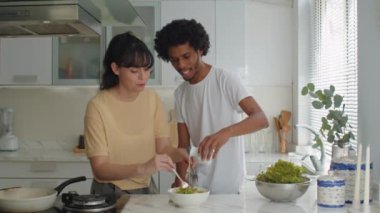 Evde kahvaltı hazırlarken salata malzemelerini karıştıran melez çiftin orta boy fotoğrafı.