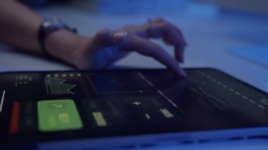 Finansal tabletleri neon ışıklarıyla kontrol eden tanınmayan bir kadının ellerini kapatın.
