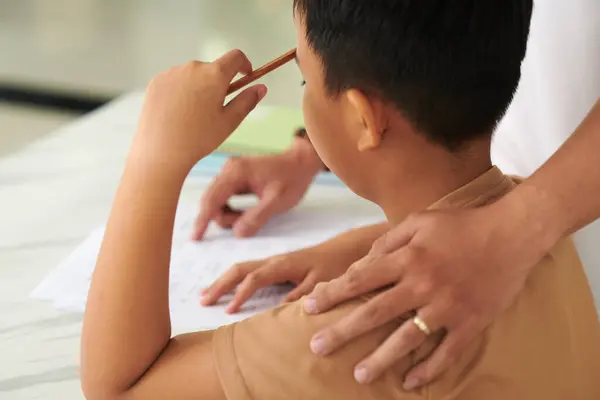 stock image Father patting son on shoulder to support him when he is doing homework