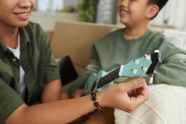 Baba, oğlunun ukulele akort etmesine yardım ediyor.