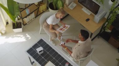 Hintli erkek yeşil enerji satış müdürünün rüzgar türbininin modelini tutarken ve bilgisayar ekranını gösterirken kadın beyaz müşteriyle konuştuğu görüntünün hemen üstünde.