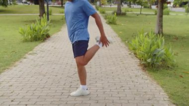 Tanımlanamayan aktif bir adamın hafta sonu açık havada antrenman yaparken bacaklarını vücuduna doğru çekmesi.