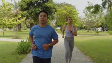 Maraton antrenmanı yaparken parkta koşan çift ırklı sporcu çiftin yavaş çekimleri.
