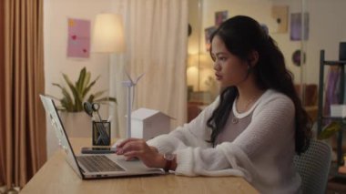 Evden online kursa katılırken yenilenebilir enerji hakkında bir şeyler öğrenen genç kızın yan görüntüsü