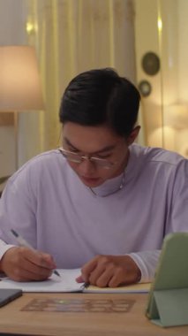 Evde ders çalışırken düşünceli ergen öğrenci ödevinin dikey çekimi