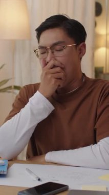 Asya kökenli erkek öğrencinin evde yapılacak sınavlara hazırlanırken uykuya daldığı dikey çekim.