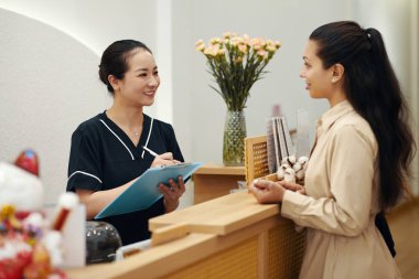 Spa salonu kozmetikçisi kişisel verilerle form dolduruyor.