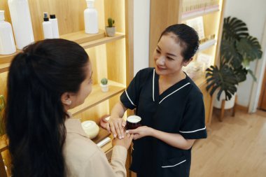 Güzellik uzmanı, müşterisinin ellerine sürdüğü vücut losyonunu beğenip beğenmediğini soruyor.