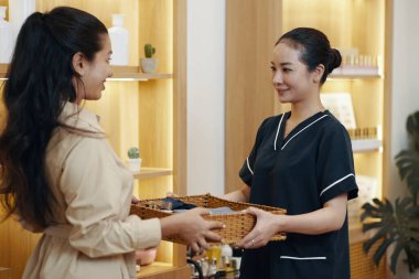 Masör müşteri sepetine temiz havlu veriyor.