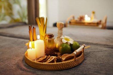 Hasır tepside yanan mumlar, aroma yağları ve spa işlemi için meyveler.