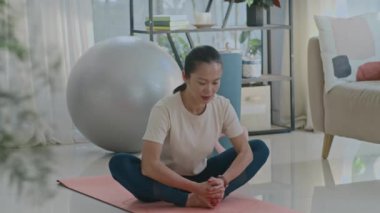 Asyalı bayan sporcunun Lotus 'un evinde poz verirken mindere uzandığı uzun bir çekim.