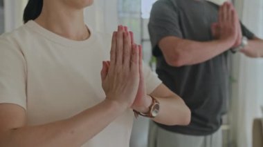 Yetişkin çiftlerin evde meditasyon yaparken el ele tutuşmalarını çek.