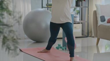 Kendinden emin, olgun Asyalı bir kadının yoga eğitimi sırasında minder üzerinde durduğu pozu çek.