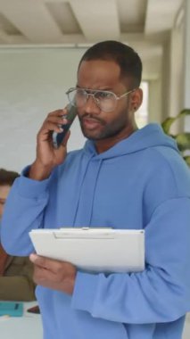 Asyalı danışman yöneticinin başlangıç şirketinin ofisinde cep telefonuyla konuştuğu dikey çekim