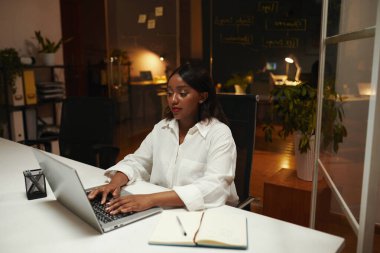 Koyu renkli ofisteki masamda dizüstü bilgisayarda çalışan geliştirici