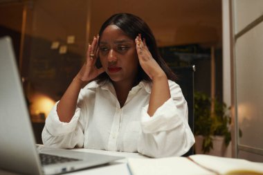 Sorunu çözemediğinde baş ağrısı çeken stresli bir kadın