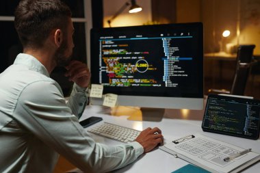 Bilgisayar ekranında programlama koduna bakan düşünceli geliştirici